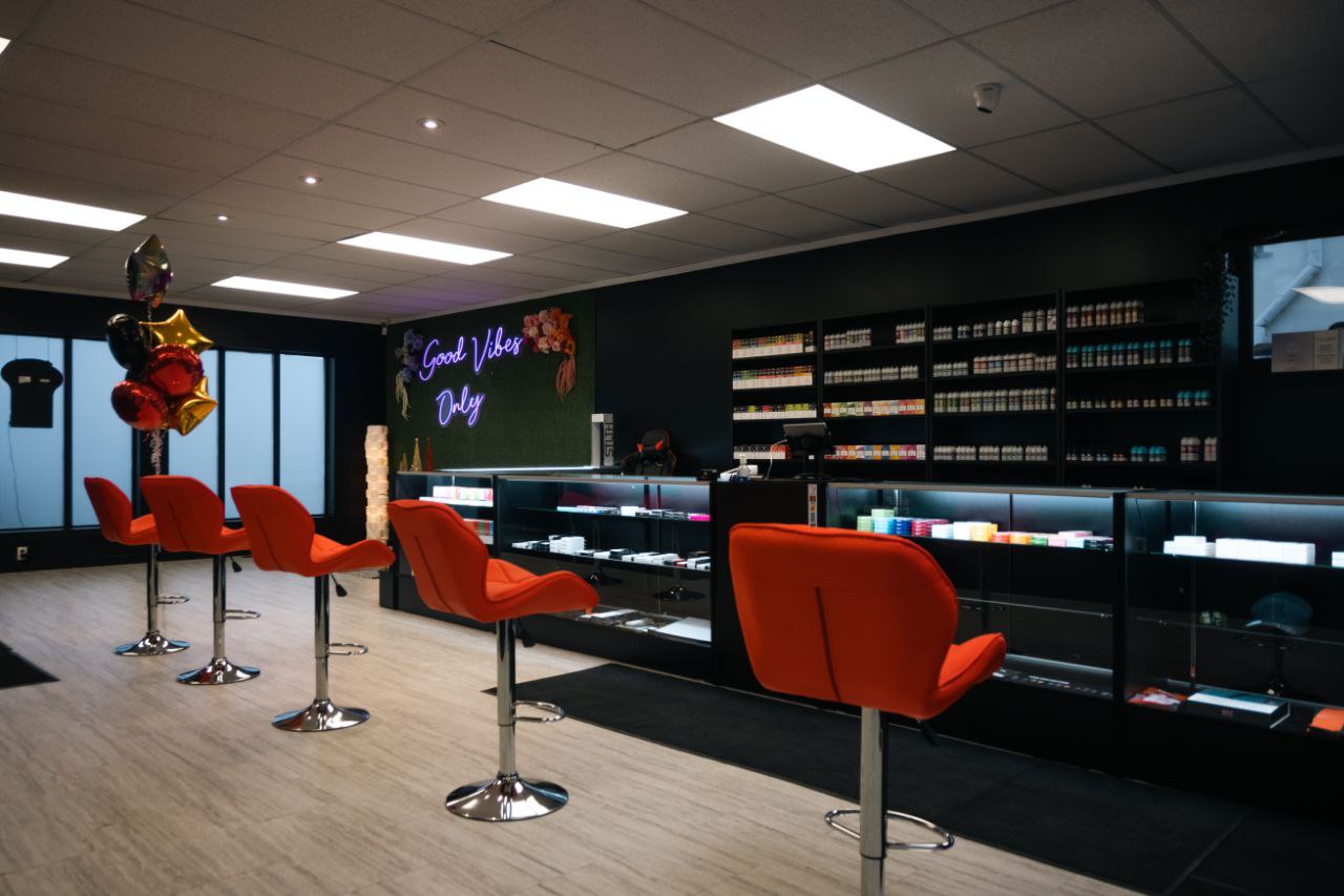 Bar area with red chairs and a dark wall with shelves.
